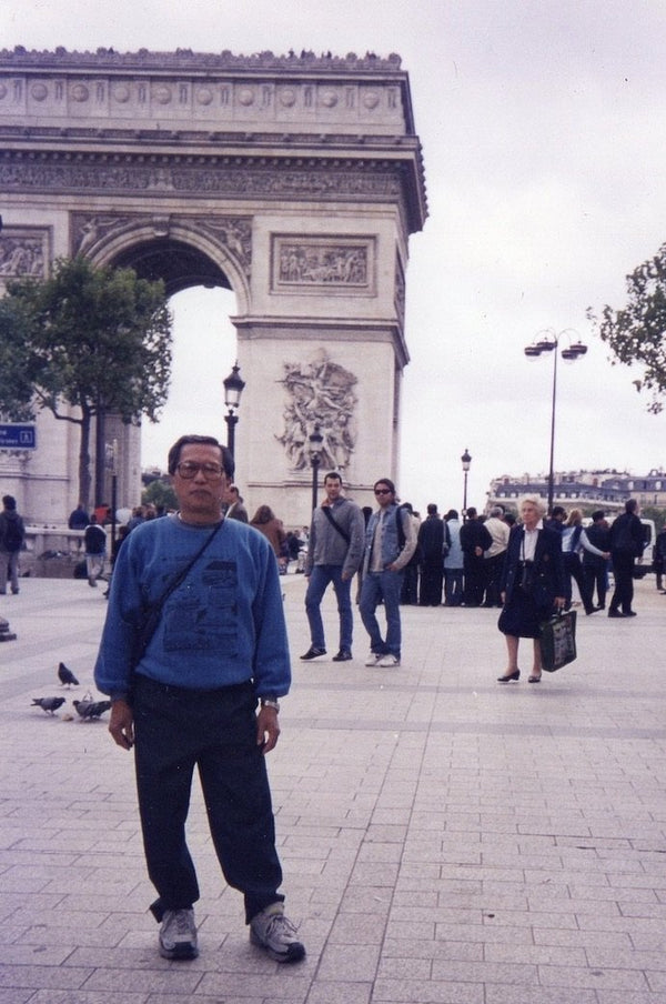 Our artist Low Hai Hong is a Singapore artist. ARTualize is the only art gallery in Singapore that represents him and his works.  A sixty year old Low Hai Hong standing in front of the Arc de Triomphe in Paris. Wearing a sweater, he looks on confidently.