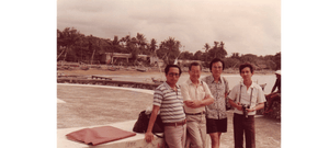 Our artist Low Hai Hong is a Singapore artist. ARTualize is the only art gallery in Singapore that represents him and his works.  A yellowish photo of a group of 4 young men by a boat with a river behind them with no buildings in sight in Bali.